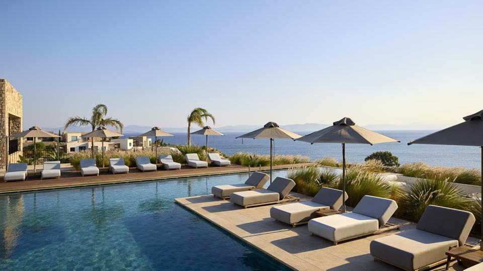 Ligbedjes aan het zwembad bij Koia All-Suite Wellbeing Resort, uitkijkend over de zee