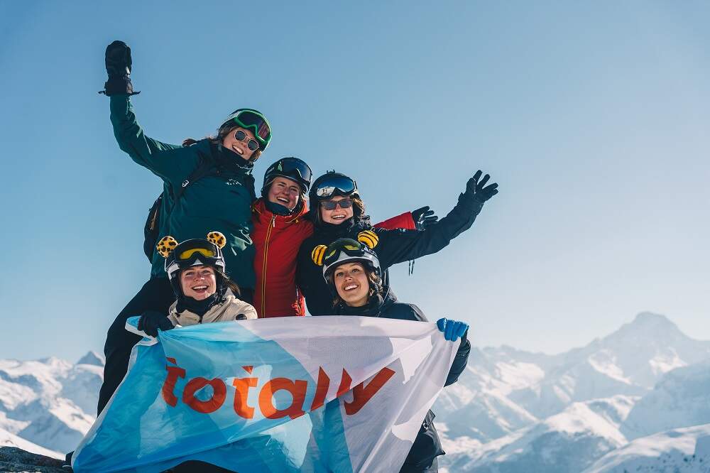 Un groupe d'étudiants au ski brandissant le drapeau Totally