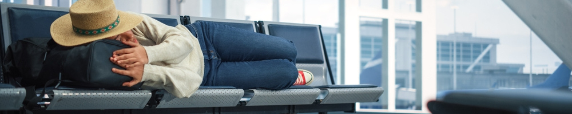 Femme faisant une sieste à l'aéroport avec chapeau de paille sur la tête