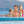Famille dans grande piscine à débordement, avec falaises en arrière plan