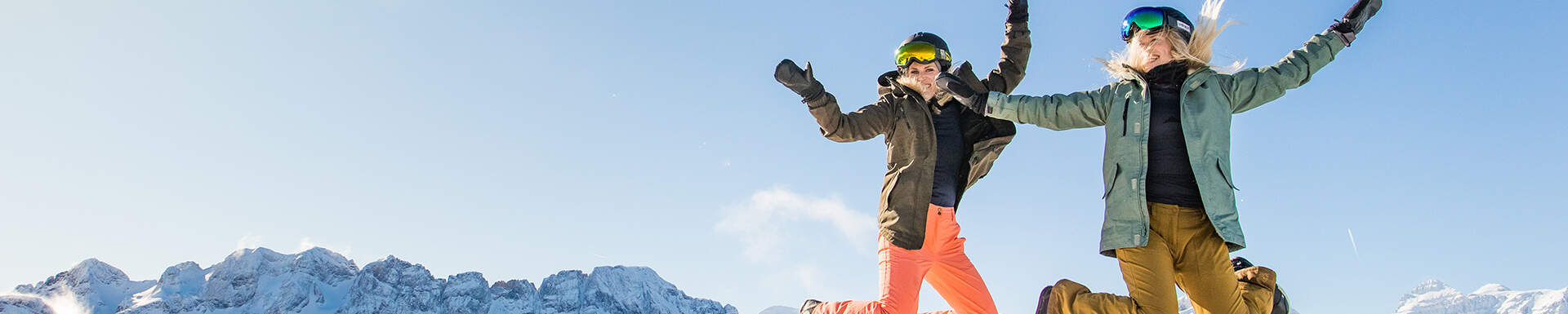 2 filles snowboardeuses sautant dans les airs en montagne