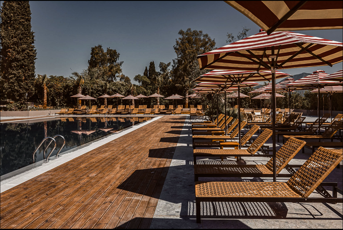 Transats style bohème en bord de piscine avec parasols rayés blancs et rouges, Hôtel Cook's Club