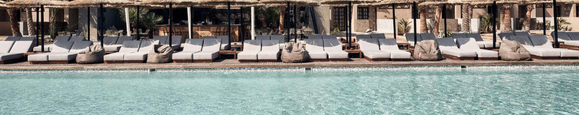 Chaises longues en bord de piscine, dans un décor bohème, hôtel Cook's Club
