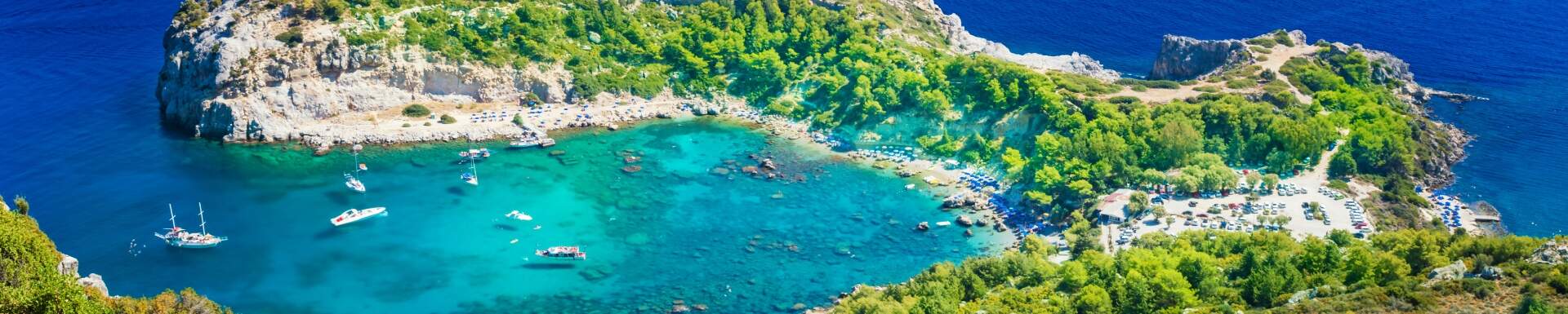 Vue d'en haut mer cristalline et bateaux, entourée de falaises verdoyantes, Rhodes, Grèce