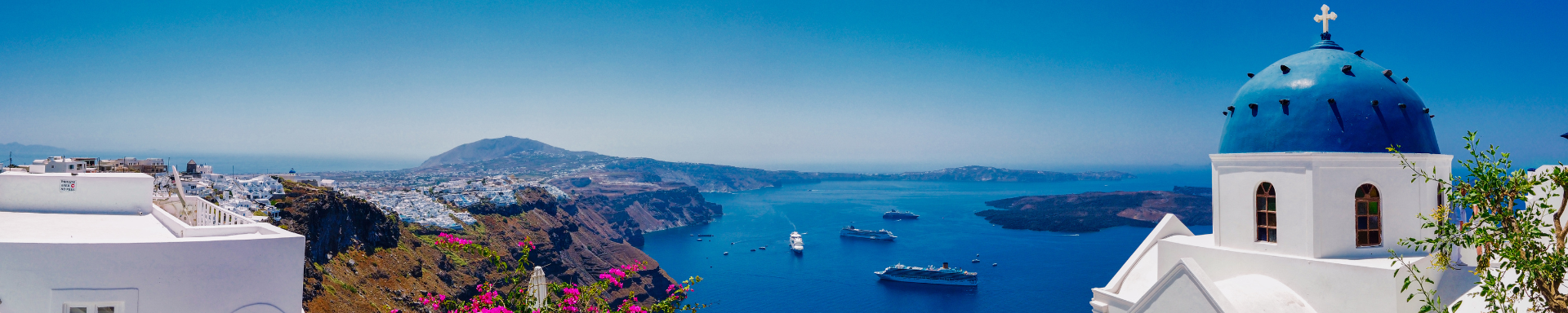 Vue panoramique sur le monastère de Nikolaus avec sa cathédrale dôme et son clocher en bord de mer sous ciel bleu à Santorin Grèce