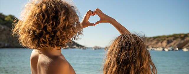 enfants faisant un coeur avec les doigts à la mer