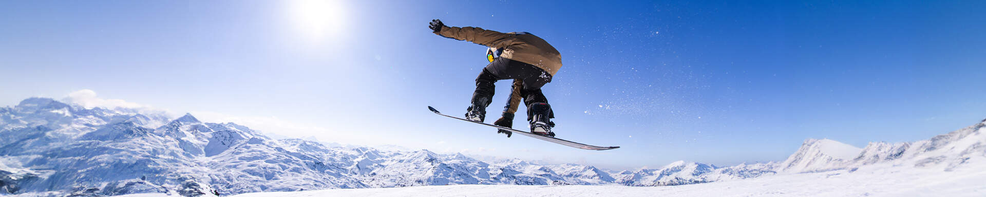 snowboarder grijpt snowboard tijdens sprong op zonnige skipiste