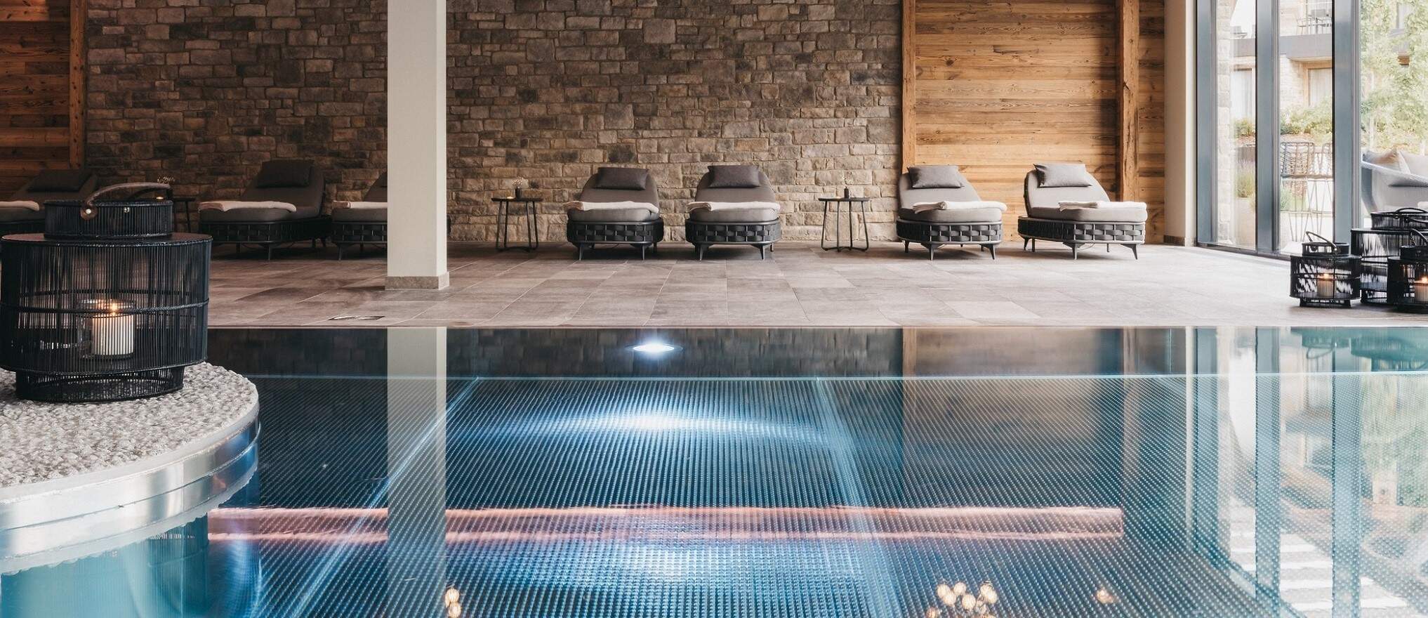 zwembad met ligbedjes in luxe hotel in aardetinten met hout en steen