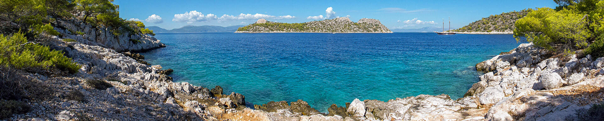 Uitzicht vanaf baai met rotsen over diepblauwe zee en eiland in het midden