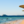 Blauwe zee met jacht in de verte aan goudgeel zandstrand met rijen parasols in Sharm el Sheikh egypte