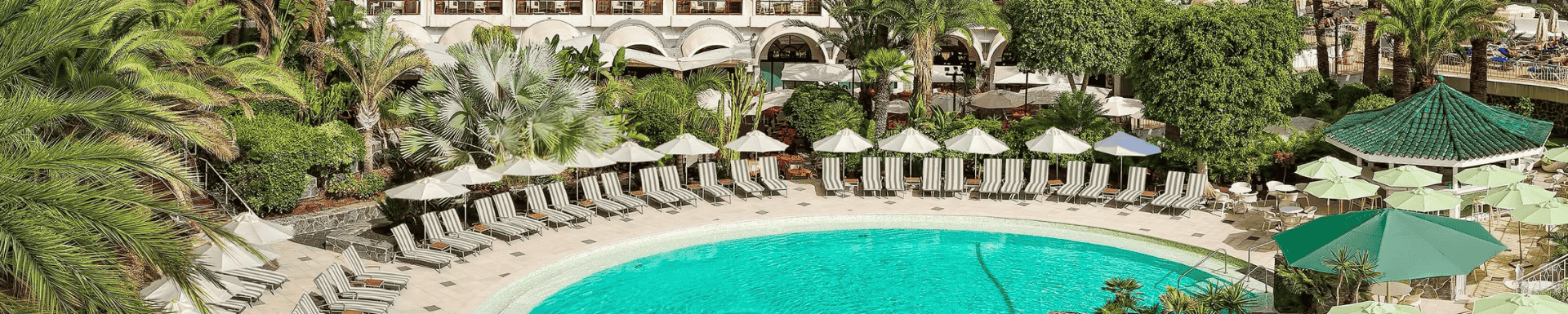 Hotel Seaside zwembad en hotel met palmbomen en ligstoelen