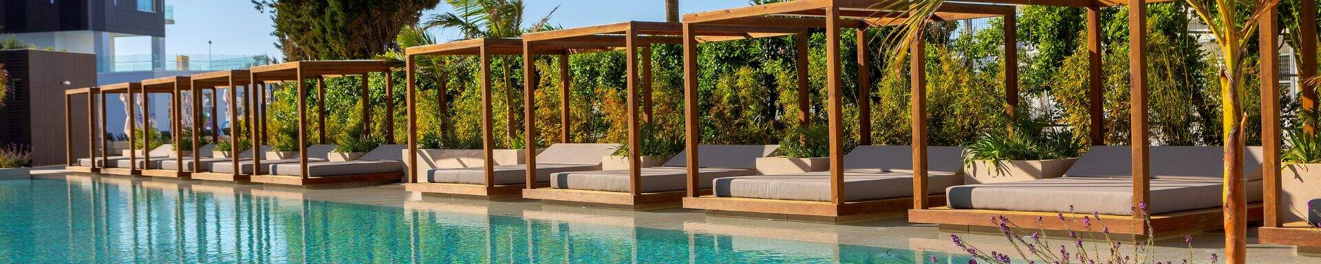 Zwembad met luxe ligbedden en palmbomen op de achtergrond