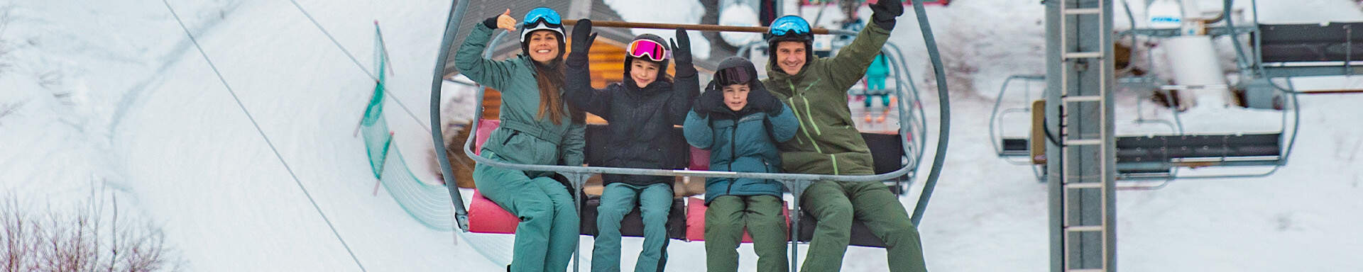 Een gezin naast elkaar zittend in een skilift