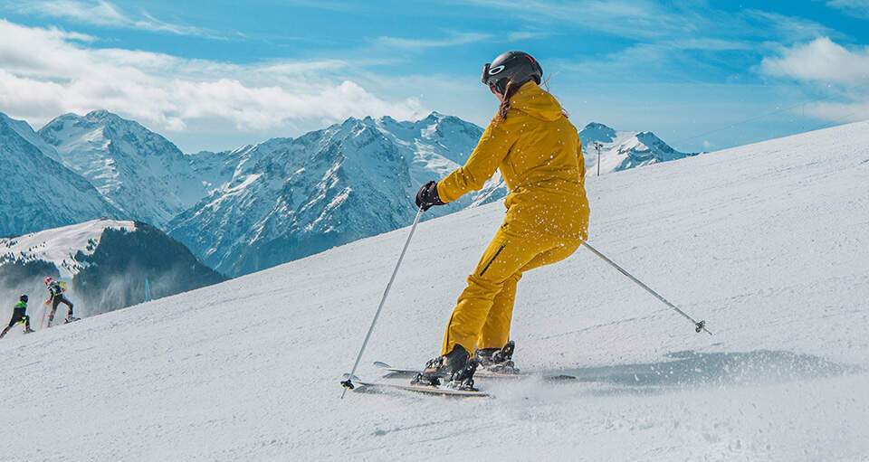 Iemand skiet in een geel pak van een besneeuwde berg af