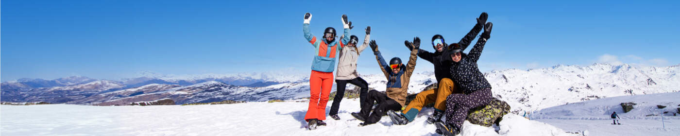 groep vrienden met handen omhoog op besneeuwde bergtop in skigebied