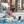 vrouw zit geknield naast zwembad en speelt met kinderen in het water met gekleurde ballen