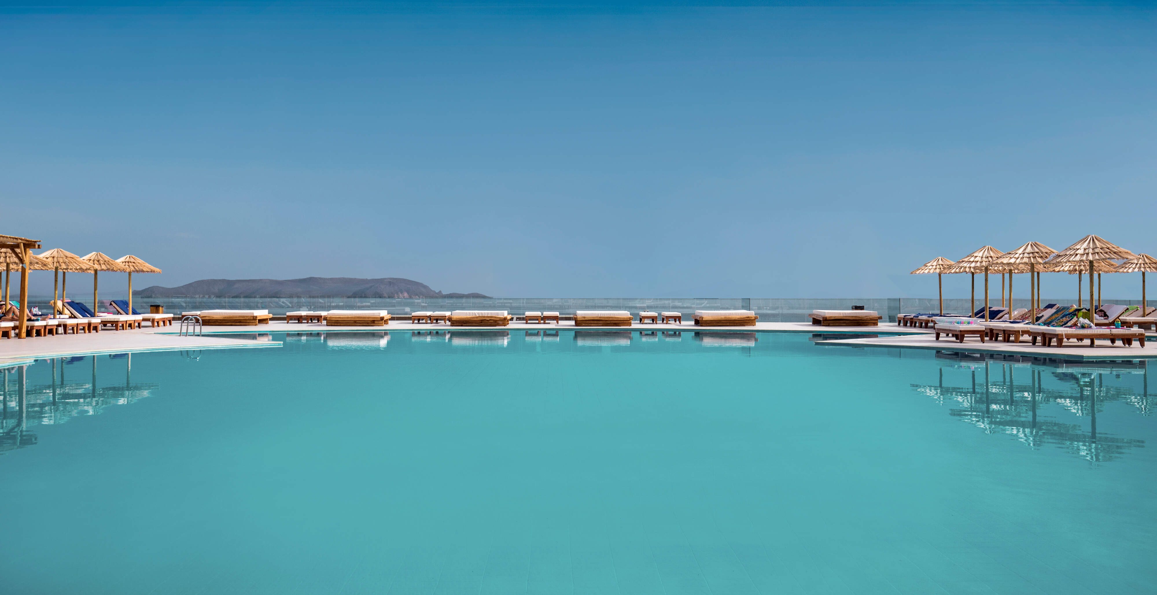 Mitsis zwembad met ligbedjes en een blauwe lucht