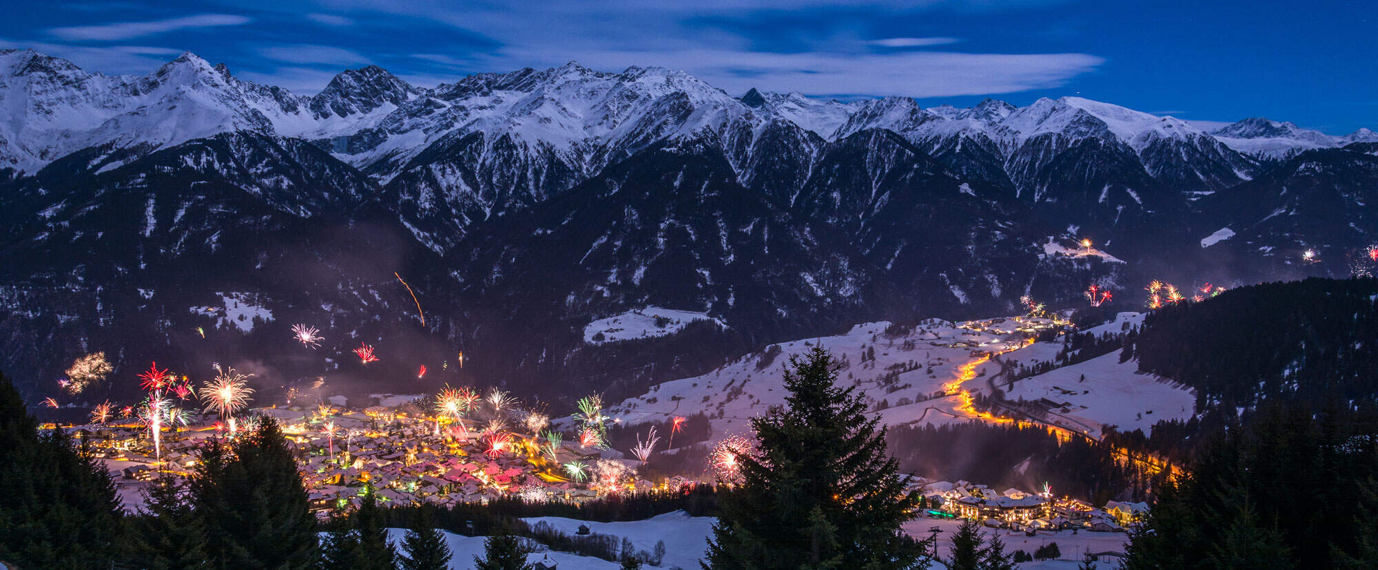 skigebied tijdens oud en nieuw met vuurwerk en verlichte bergen met sneeuw